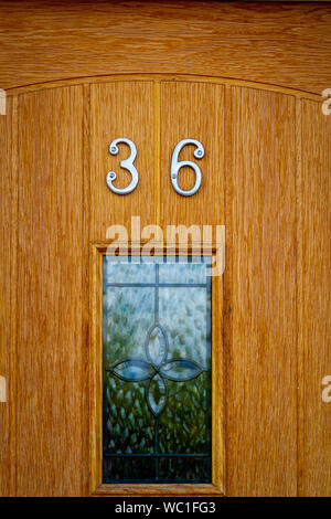 House number 36 on a natural grained and varnished wooden door with stained glass insert Stock Photo