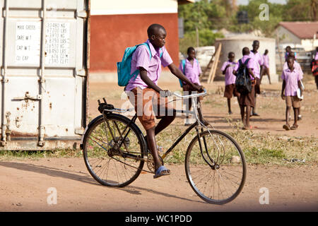 TORIT, SOUTH SUDAN-FEBRUARY 20, 2013: Unidentified schoolboy rides his bicycle from school in South Sudan Stock Photo