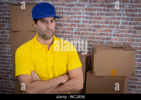 Brazilian mailman with arms crossed in a deposit with a a lot of boxes. Stock Photo