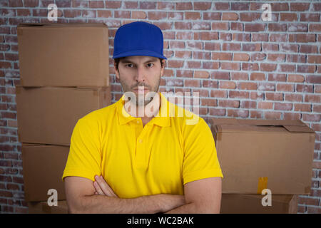 Brazilian mailman with arms crossed in a deposit with a a lot of boxes. Stock Photo