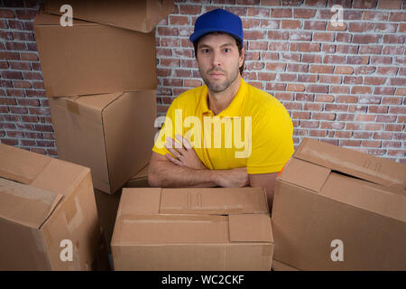 Brazilian mailman with arms crossed in a deposit with a a lot of boxes. Stock Photo