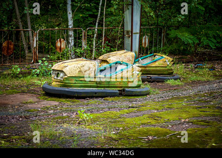 Old broken children's electric cars in an amusement park, a recreation park in the city of Pripyat. Chernobyl nuclear power plant exclusion zone Stock Photo