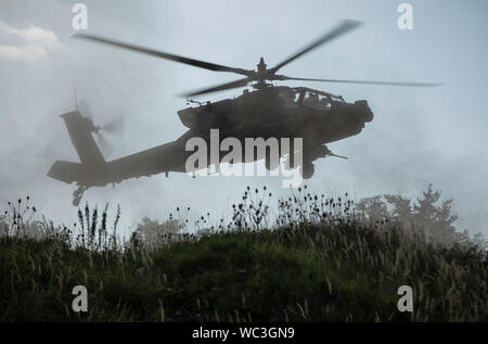 An AH-64 Apache Attack Helicopter with the 1st Squadron, 6th Cavalry Regiment, 1st Combat Aviation Brigade, 1st Infantry Division hovers in a field during a simulated attack mission, as part of the culminating force on force exercise of Combined Resolve XII at the Joint Multinational Readiness Center in Hohenfels, Germany Aug. 22, 2019. Combined Resolve is a biannual U.S. Army Europe and 7th Army Training Command-led exercise intended to evaluate and certify the readiness and interoperability of US forces mobilized to Europe in support of Atlantic Resolve.  (U.S. Army photo by Sgt. Thomas Mort Stock Photo