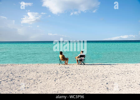 Salda lake like Maldives with white sand and turquoise colored water. One Couple sitting on portable chairs near the waters edge. Burdur / Turkey. Mou Stock Photo