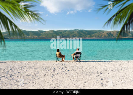 Salda lake like Maldives with white sand and turquoise colored water. One Couple sitting on portable chairs near the waters edge. Burdur / Turkey. Stock Photo