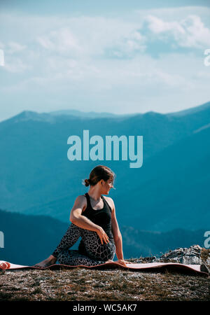 Portrait of the attractive woman is practicing yoga on the rock above river Stock Photo