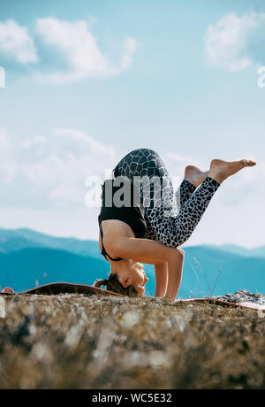 Yoga, fitness woman doing yoga headstand exercises in the mountain peak Stock Photo