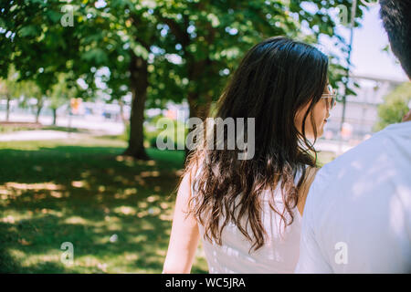 Beautiful happy young couple backside outdoors in summer park under trees Stock Photo