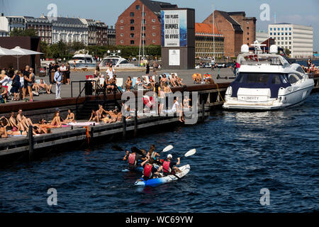 Copenhagener and tourists at the wooden pier at the Ofelia Beach near the Royal Play House and the  historic Nyhavn in Copenhagen, Denmark.  The water in Copenhagen harbor is so clean that it is safe to take a dip. In 2018 Copenhagen topped CNN’s list for “Best Cities for swimming”. Stock Photo