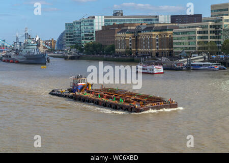 A large barge in the Pool of London, River Thames by HMS Belfast and Hays Galleria on the South Bank of the Embankment, viewed from London Bridge