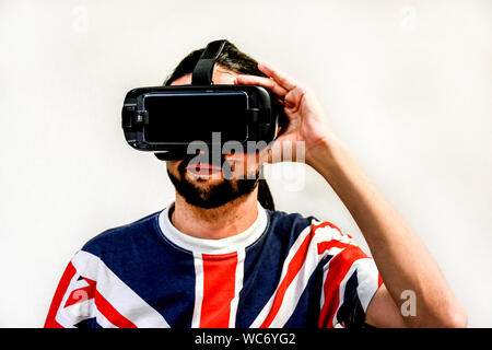 Man on white background with Virtual Reality headsets on, experimenting and testing new VR technology. Man with 4K Glasses watching games or videos. Stock Photo