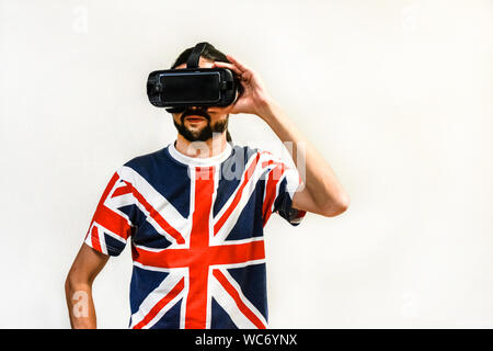 Man on white background with Virtual Reality headsets on, experimenting and testing new VR technology. Man with 4K Glasses watching games or videos. Stock Photo