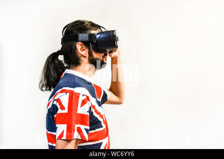 Man on white background with Virtual Reality headsets on, experimenting and testing new VR technology. Man with 4K Glasses watching games or videos. Stock Photo