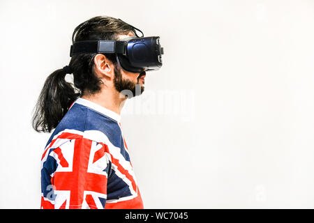Man on white background with Virtual Reality headsets on, experimenting and testing new VR technology. Man with 4K Glasses watching games or videos. Stock Photo