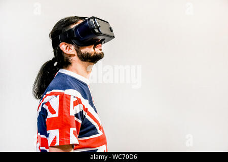 Man on white background with Virtual Reality headsets on, experimenting and testing new VR technology. Man with 4K Glasses watching games or videos. Stock Photo