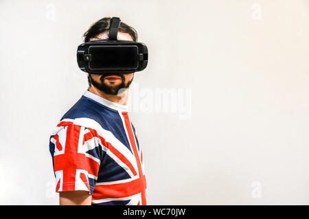 Man on white background with Virtual Reality headsets on, experimenting and testing new VR technology. Man with 4K Glasses watching games or videos. Stock Photo
