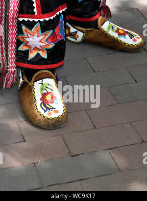 A Native American man wearing traditional Ojibwe beaded moccasins participates in a Native clothing contest at Santa Fe Indian Market in Santa Fe, NM. Stock Photo