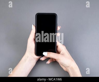Womans hand holding black screen mobile phone Stock Photo