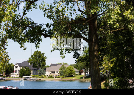 Suburban waterfront homes seen through the trees along Geist Lake in Hamilton County, Indiana, USA. Stock Photo