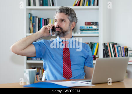 Mature businessman with beard talking with client at office of company Stock Photo