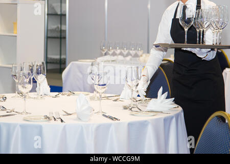 Waitress dressed in the uniform serving a set of wine glasses -selected focus Stock Photo