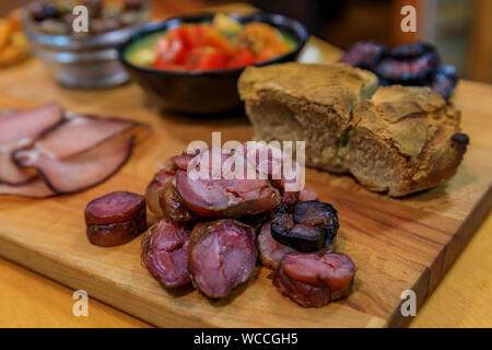 Board of traditional Portuguese food with blood and pork sausage, ham, bread, tomatoe salad and olives at a restaurant in Porto Stock Photo