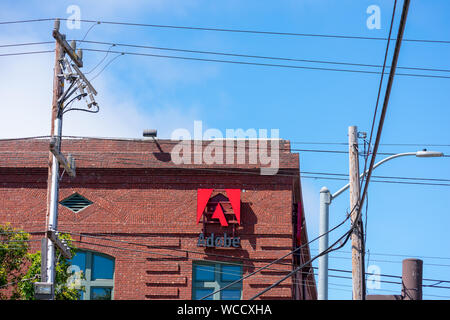 Adobe logo on the brick office facade of computer software company focused upon the creation of multimedia and creativity software products Stock Photo