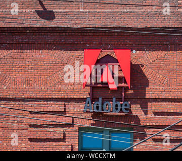 Adobe logo on the brick office facade of computer software company focused upon the creation of multimedia and creativity software products Stock Photo
