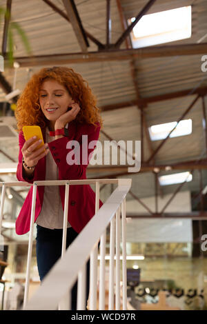 Red-haired office worker using phone enjoying little break Stock Photo