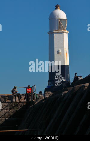 The old lighthouse on the end of the jetty at Porthcawl which is famous for its tall waves during storms which dwarf the two storey building adjacent. Stock Photo