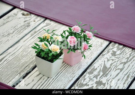 Artificial flowers in pots on the table. Table setting Stock Photo