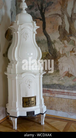 Decorative masonry heater placed in the room corner. Stock Photo