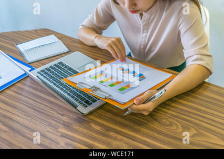 Asian office employee checking sales statistics report at workplace Stock Photo
