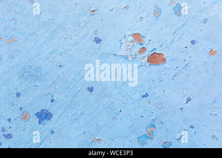 Close-up of a weathered and worn sheet metal plate painted in light blue. Paint is partly peeled off revealing rusty metal. Abstract background. Stock Photo
