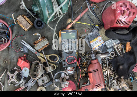 Workshop desktop of electrician repairman. Clutter on a desk full of appliances and components for repairing electrical appliances and accessories. Stock Photo