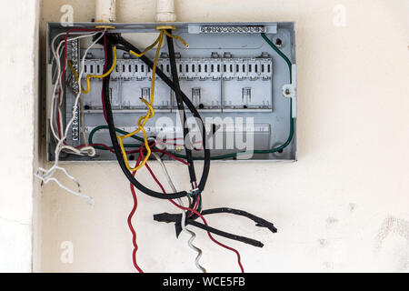 A open empty electricity fuse box with cables on white wall. Electrical control panel with empty fuse boxes inside an abandoned building. Damaged circ Stock Photo