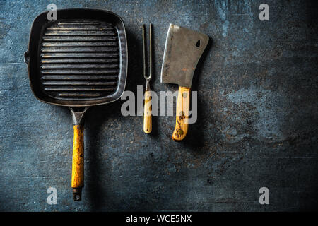 Vintage grill pan butcher and fork on dark concrete table Stock Photo