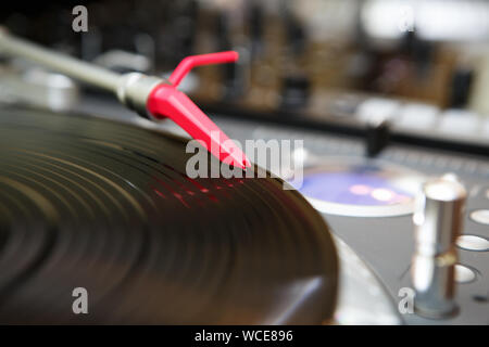 Red turntables needle on tone arm.Professional dj turn table player with old analog record in close up.Concert stage equipment for disc jockey.High qu Stock Photo