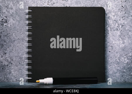 White marker and notebook for sketches with black sheets on the table with copy space Stock Photo