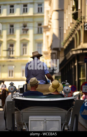 A horse carriage with tourists drives through the streets of downtown Vienna. Austria Stock Photo