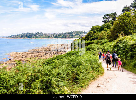 A family with children is walking towards Perros-Guirec on the 'sentier des douaniers', the GR34 coastal path along the Pink Granite Coast in Brittany