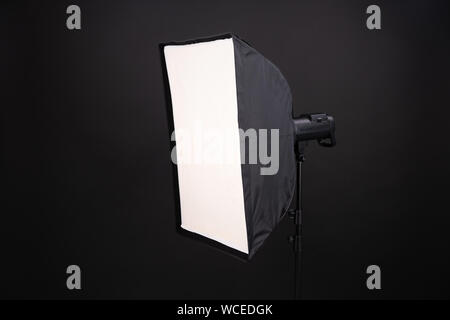 A softbox on the black background. A professional stripbox. Photo studio equipment. Flashlight and outbreak. Stock Photo