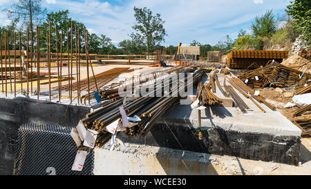 Construction site. Rebars, ferroconcrete, ceiling concrete, waterproofing and formwork. Steel bar reinforcement on building. Blue sky and green trees. Stock Photo