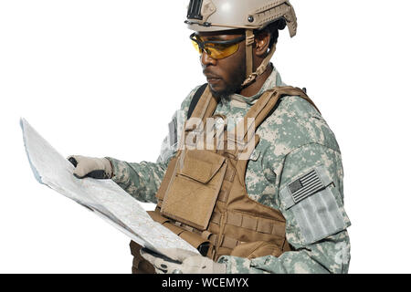 American soldier wearing uniform and helmet holding map and looking at locality objects. African male soldier in armour navigating with map. Concept of army. Stock Photo