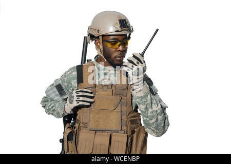 American male radio installation for remote communication and listening answers. African man wearing army uniform and big armour on chest communicating with headquarters. Stock Photo