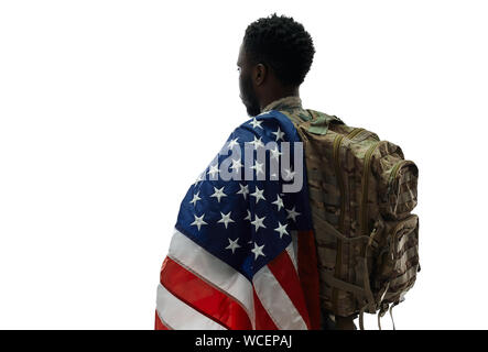 Back view of male ranker with backpack holding American flag on one shoulder and looking away. Young man going to army for protecting and serving homeland. White isolated studio background. Stock Photo