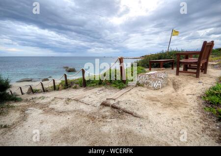 Empty Chairs On Footpath By Sea Against Cloudy Sky