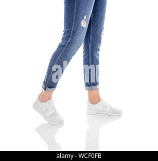 Legs in jeans and white sneakers isolated on a white background. Stock Photo