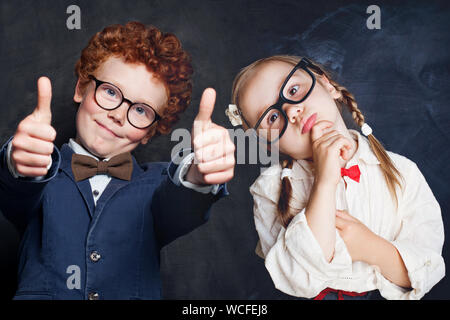 Portrait of cute happy kids in school uniform. Little boy and girl holding thumb up, thinking and smiling Stock Photo