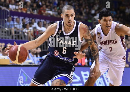 A basketball player of Greece, left, keeps the ball while defended by a member of Venezuela, right, during 2019 Suzhou International Basketball Challenge in Suzhou city, east China's Jiangsu province, 27 August 2019. Greece defeated Venezuela with 74-51 and wins the championship of 2019 Suzhou International Basketball Challenge in Suzhou city, east China's Jiangsu province, 27 August 2019. Stock Photo